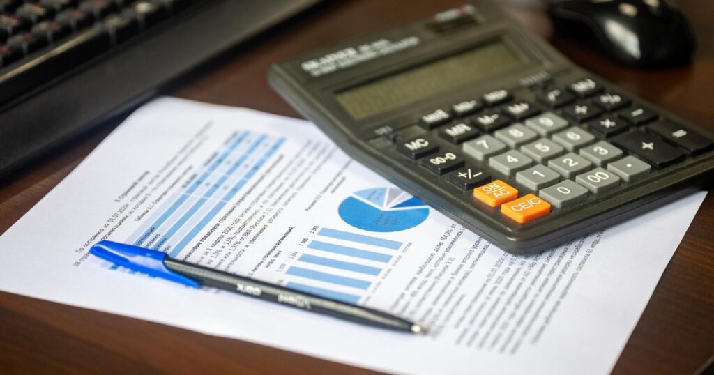 Calculator, pen and a printed financial report on a desk, illustrating how to read commercial property financials.