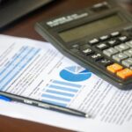 Calculator, pen and a printed financial report on a desk, illustrating how to read commercial property financials.