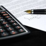 Loan documents with a signature, pen and financial calculator, illustrating commercial real estate financing.